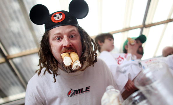 man in mouse ears eating cannoli 